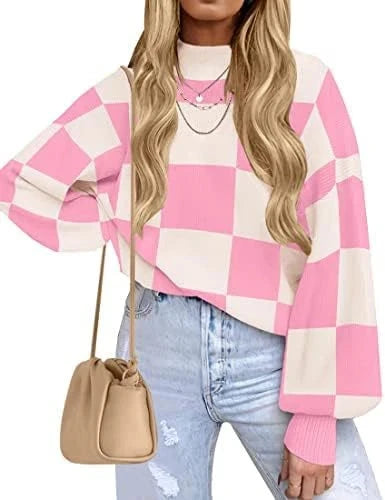 Model wearing a pink and white checkerboard knit sweater with long sleeves, styled with light-wash jeans.