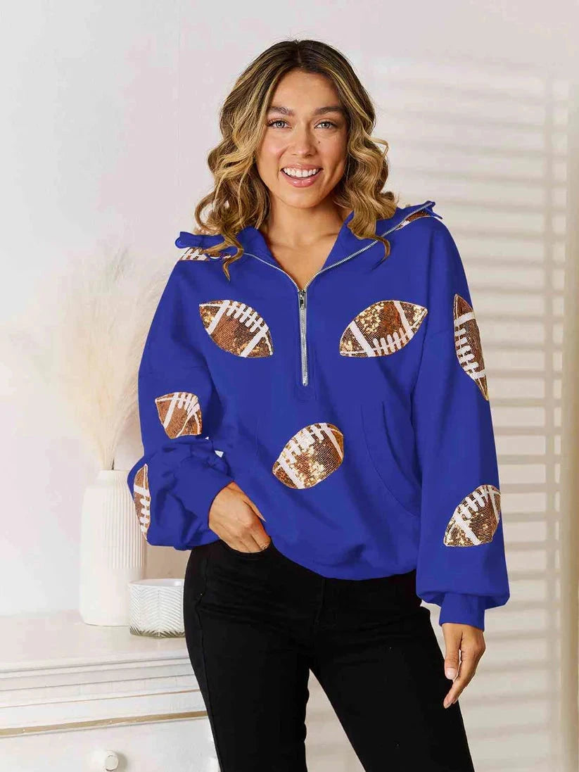 Model wearing a blue quarter-zip hoodie with football graphics on the front and sleeves.