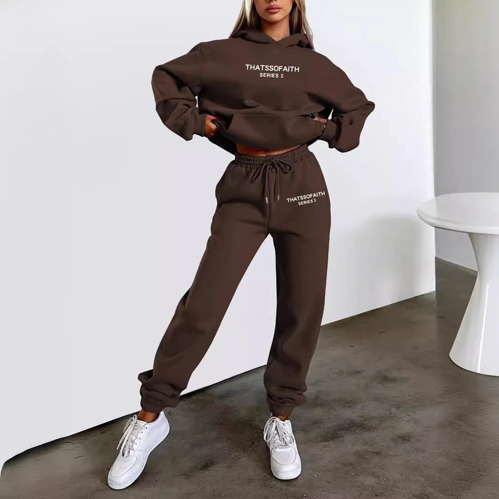 Person wearing a brown tracksuit with text, standing against a white wall.