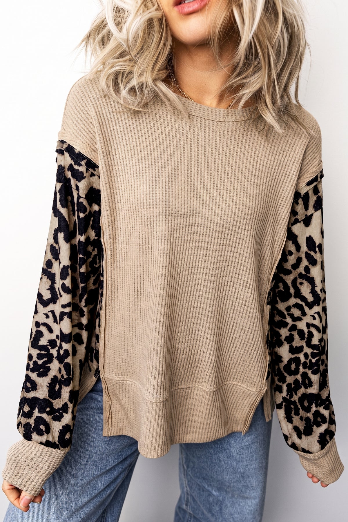 Beige waffle knit crewneck top with long leopard print sleeves, styled with blue jeans