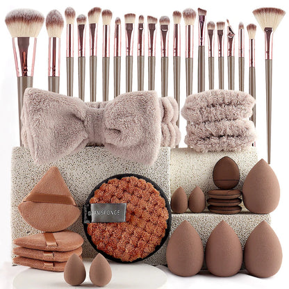 Makeup accessory set with rose gold brushes, brown blending sponges, a soft bow headband, and matching beauty tools.