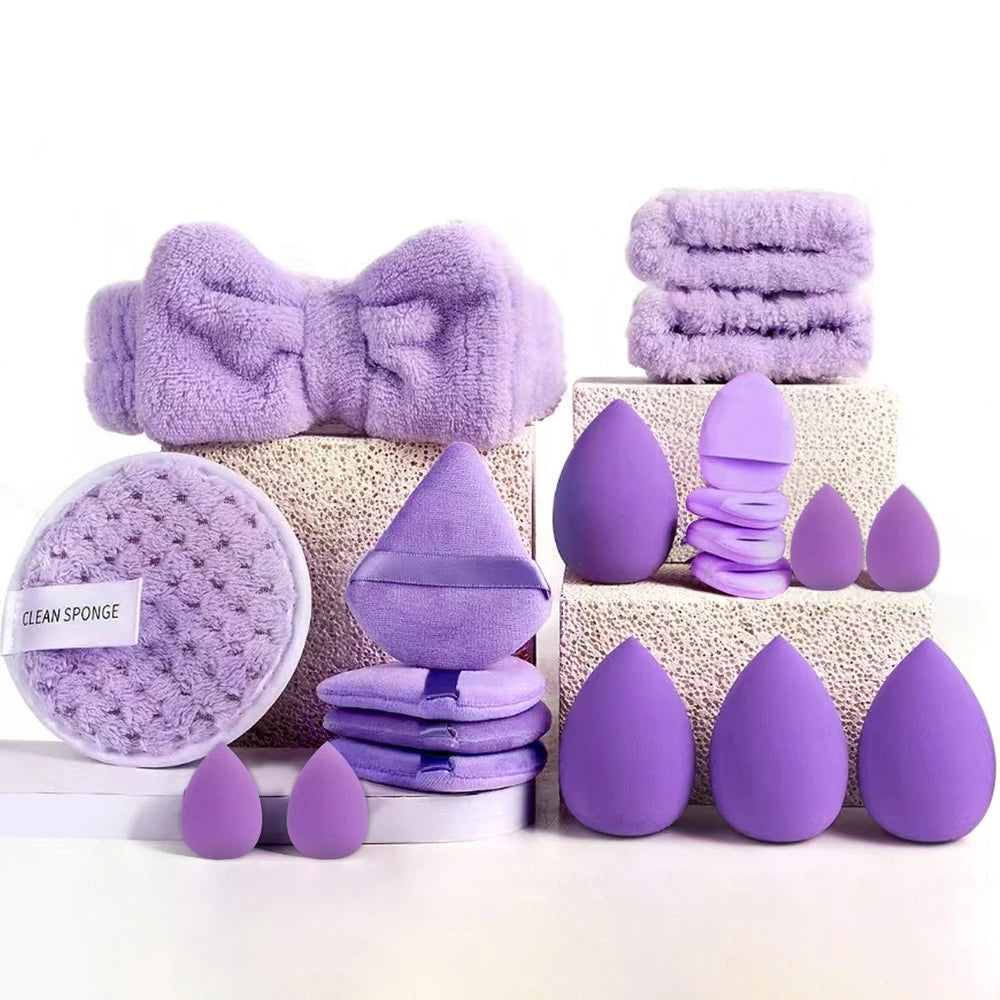 Collection of purple beauty tools including sponges and a towel on a white background