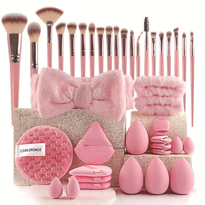 Set of pink makeup brushes, sponges, and a bow with a decorative box on a white background.
