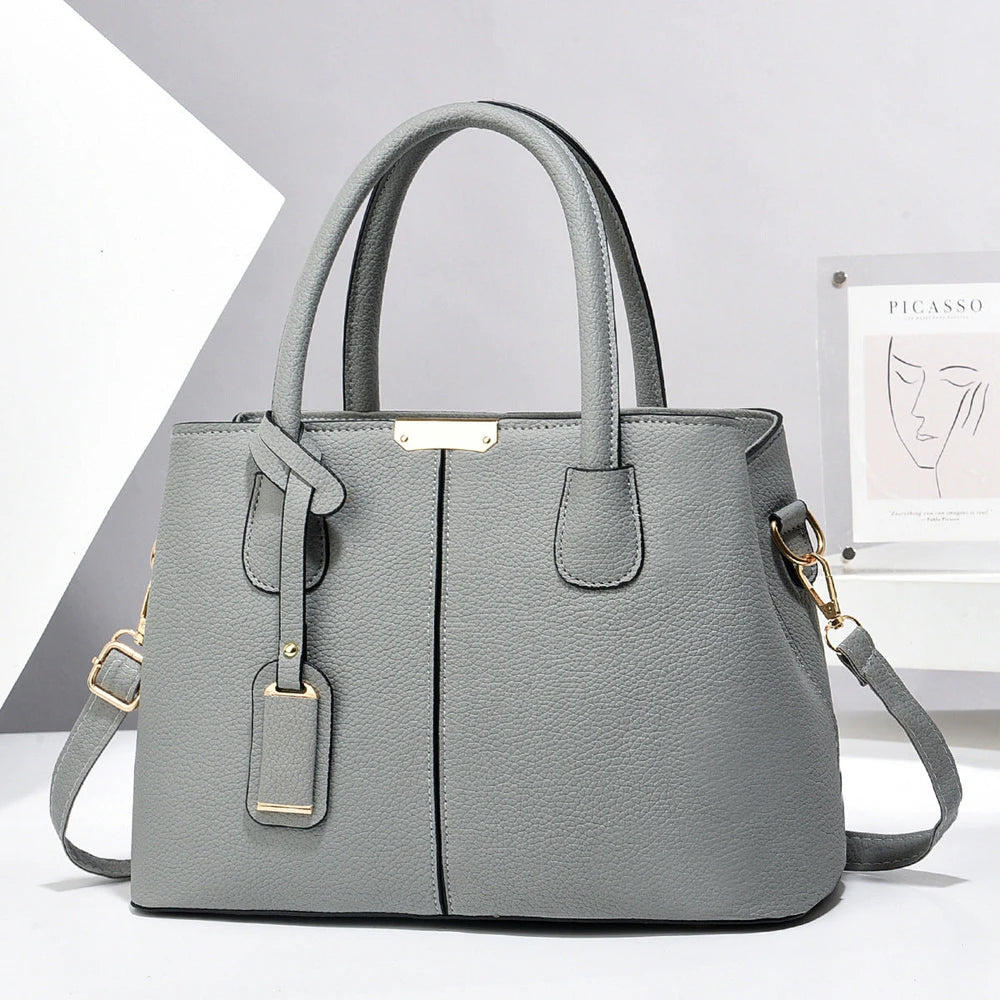 Gray handbag with gold accents on a light gray background