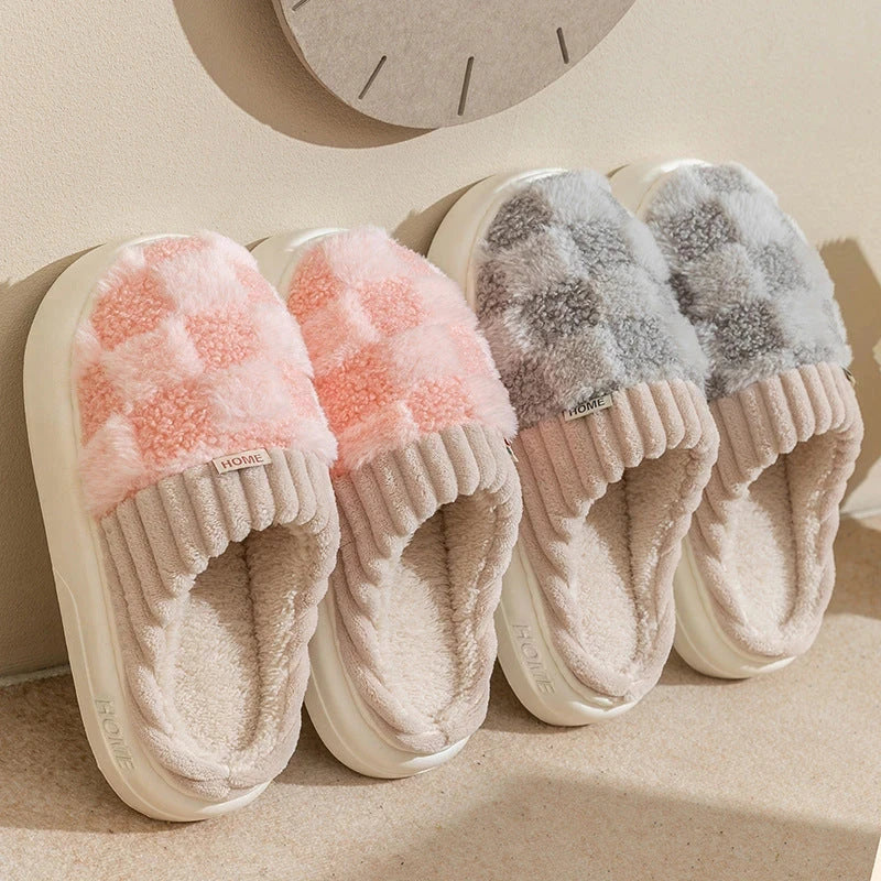  Pink and gray plush checkered slip-on house slippers with ribbed trim and light-colored soles.