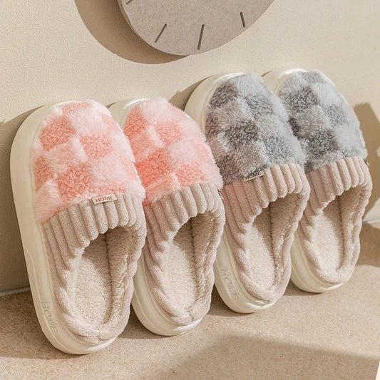  Pink and gray plush checkered slip-on house slippers with ribbed trim and light-colored soles.