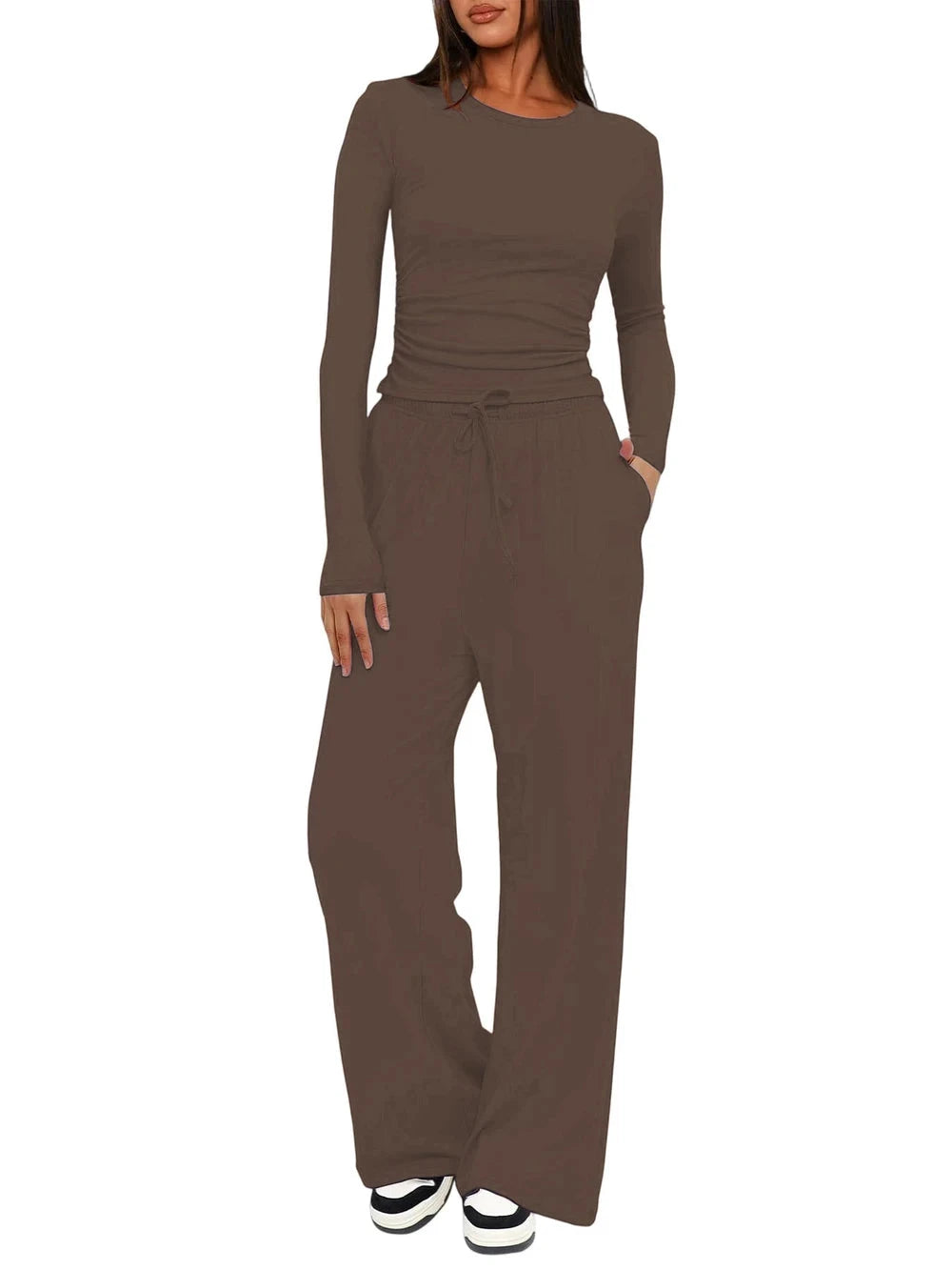 A woman modeling a matching two-piece lounge set in a solid taupe-brown color, featuring a long-sleeve crewneck top and wide-leg drawstring pants, shown against a plain white background.