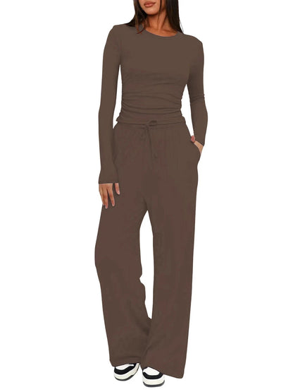 A woman modeling a matching two-piece lounge set in a solid taupe-brown color, featuring a long-sleeve crewneck top and wide-leg drawstring pants, shown against a plain white background.