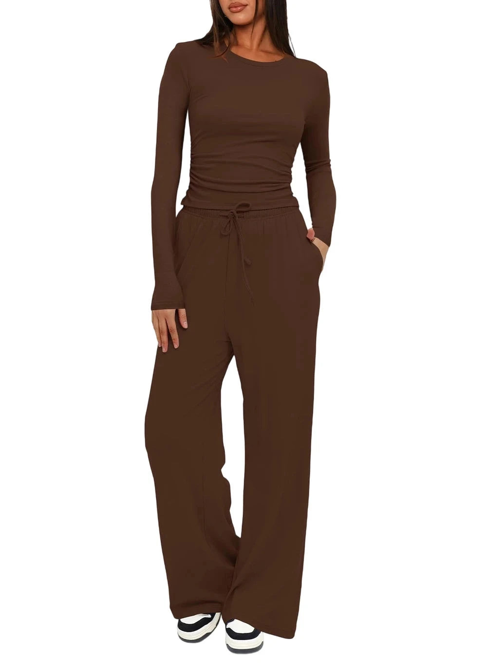A woman modeling a matching two-piece lounge set in solid dark brown, featuring a long-sleeve crewneck top and high-waisted wide-leg drawstring pants, shown against a plain white background.