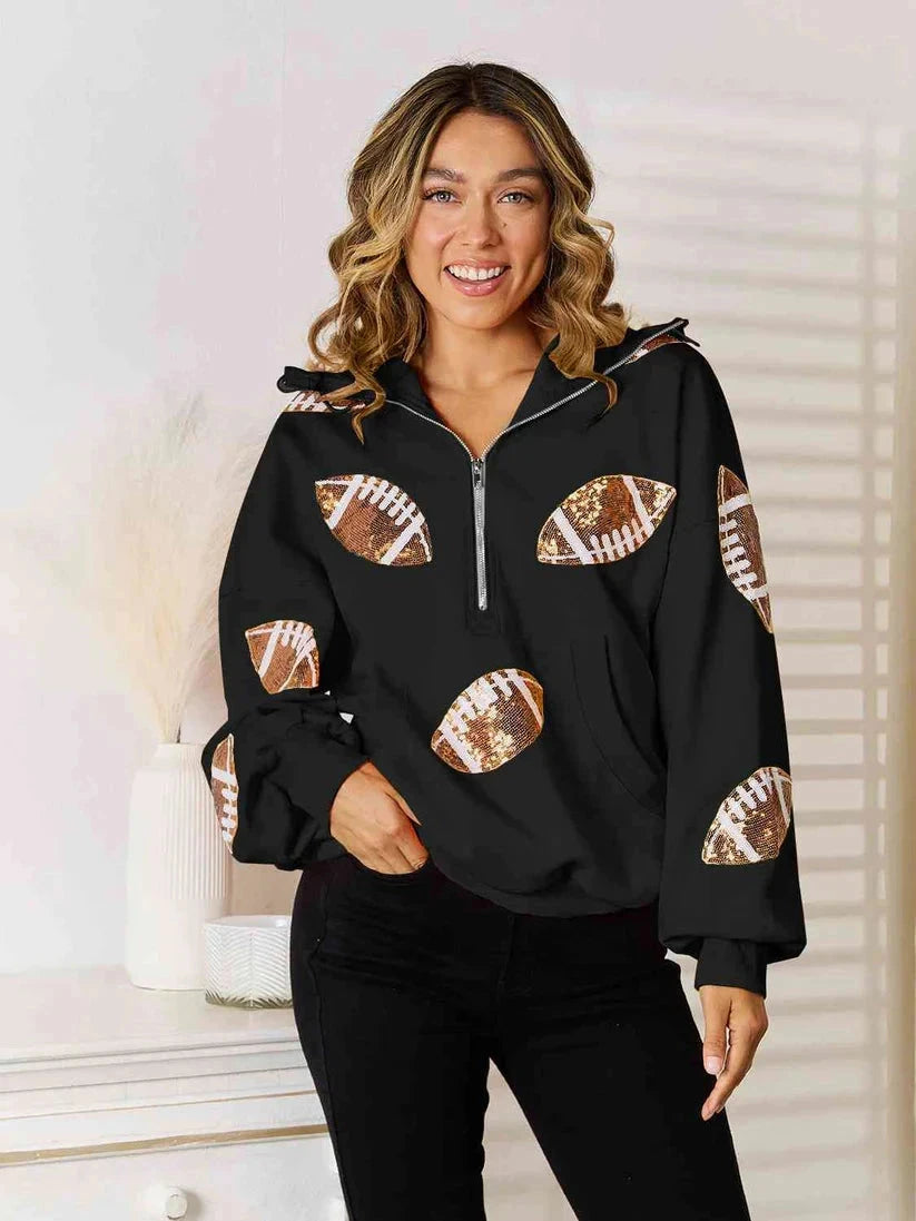 Model wearing a black quarter-zip hoodie with football graphics on the front and sleeves.