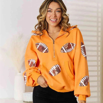 Model wearing an orange quarter-zip hoodie with football graphics on the front and sleeves.