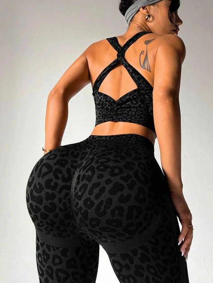 Person wearing black leopard print sports bra and leggings on a plain background