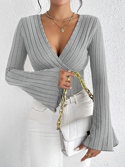 Model wearing a Grey ribbed wrap-style V-neck top with long bell sleeves, styled with white pants.