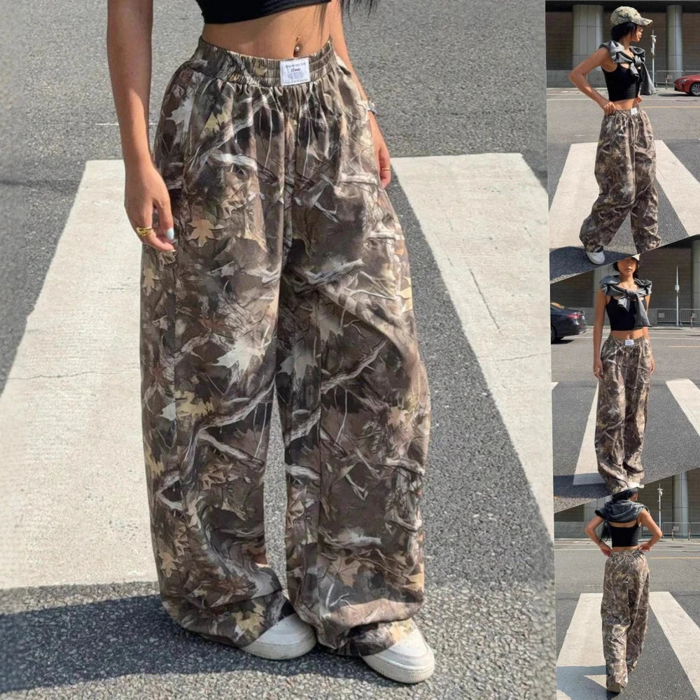 Model wearing loose woodland camouflage wide-leg cargo pants with an elastic waistband and white sneakers.
