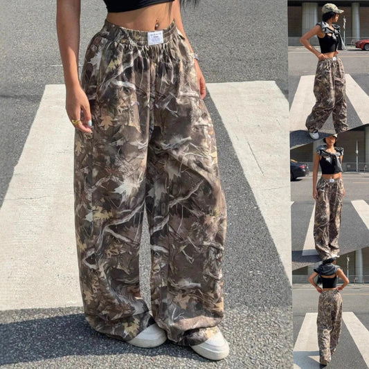 Model wearing loose woodland camouflage wide-leg cargo pants with an elastic waistband and white sneakers.