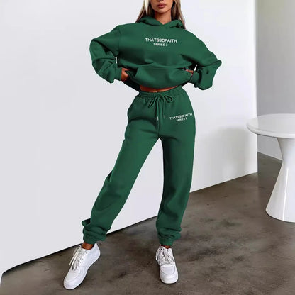 Person wearing a green tracksuit with text, standing against a white wall.