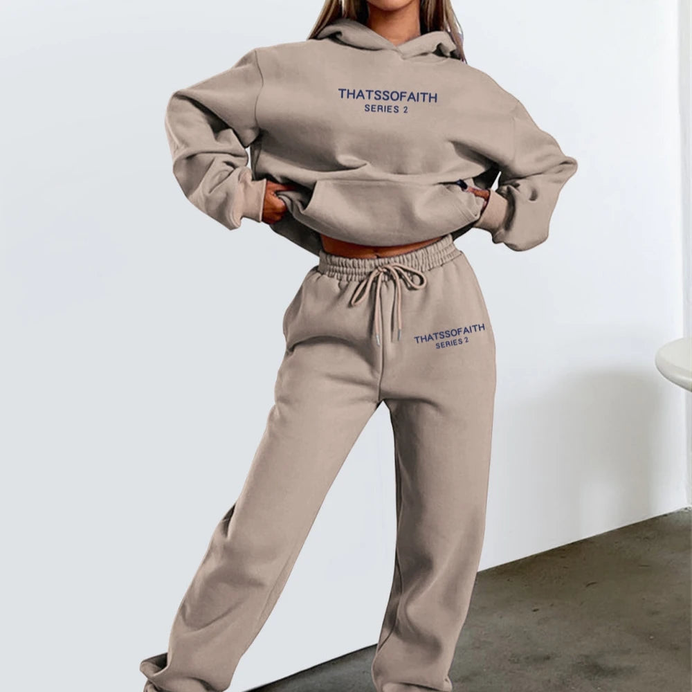 Person wearing a beige hoodie and sweatpants set with 'THATSSOFAITH' branding on a light gray background.