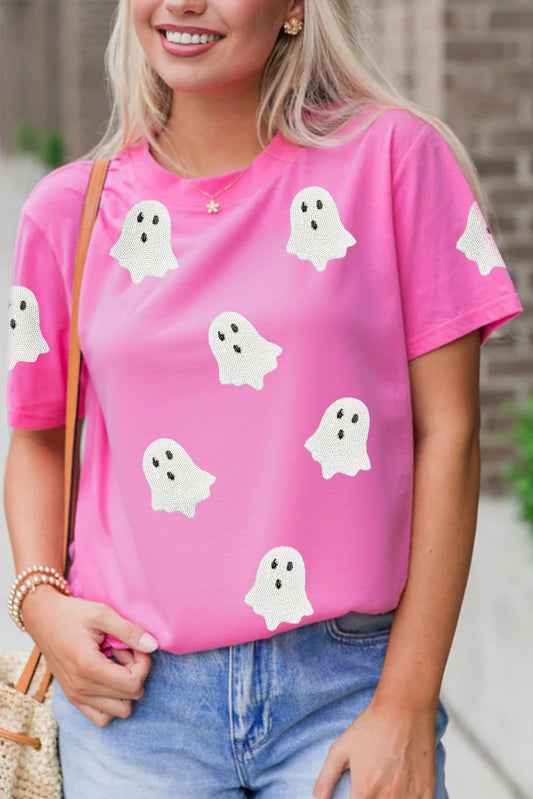 Bright pink short-sleeve T-shirt with scattered white ghost prints, styled with blue jeans.