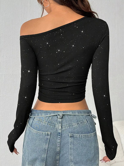 Black off-shoulder long-sleeve top with star pattern worn by a person against a neutral background